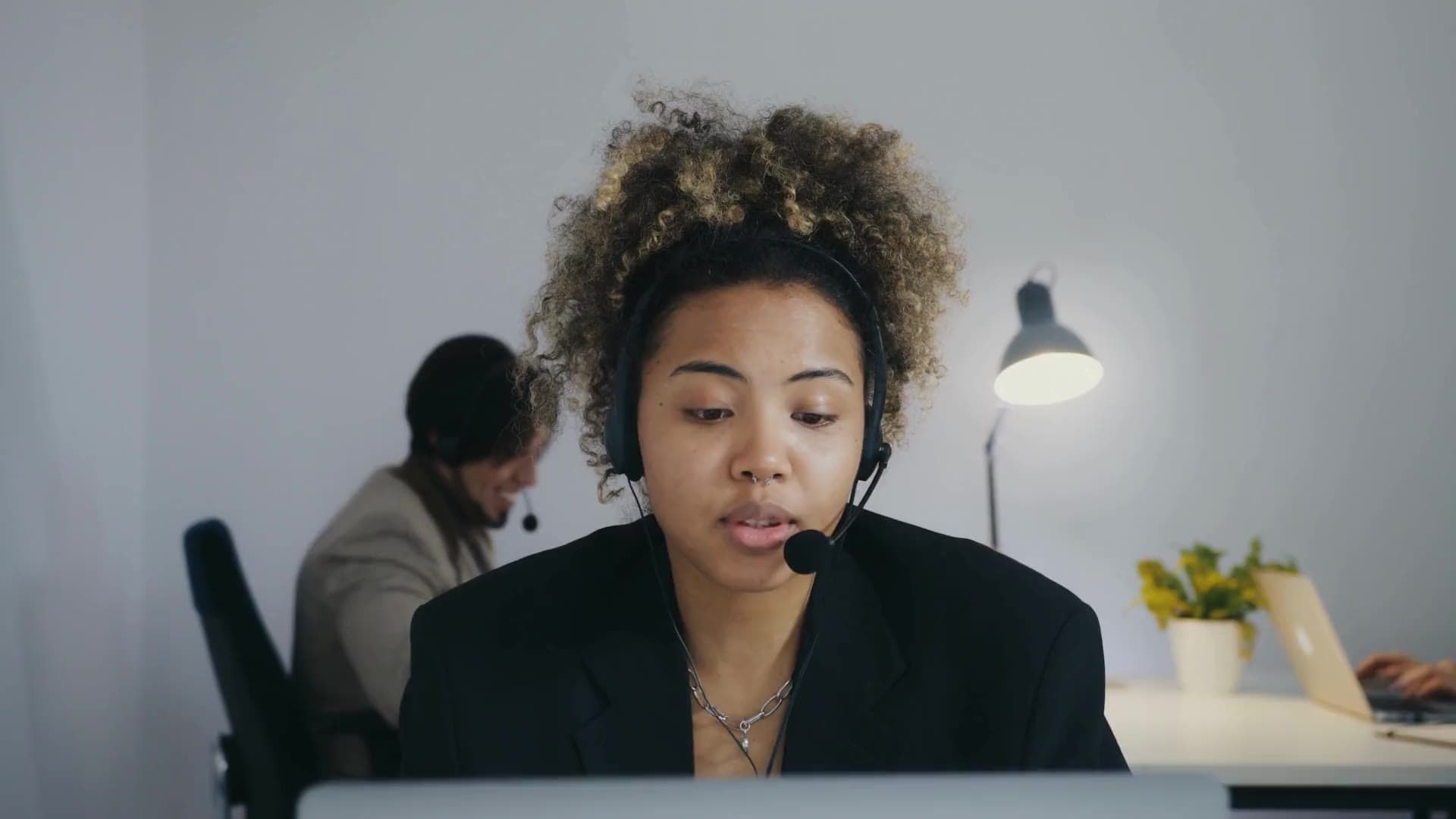 An intake specialist answering a call on a headset in a bright office